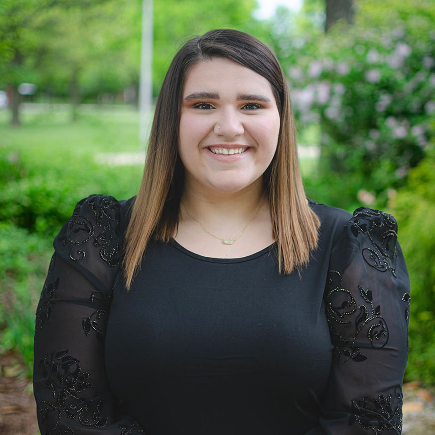 Woman dark hair wearing a black shirt with beaded sleeves