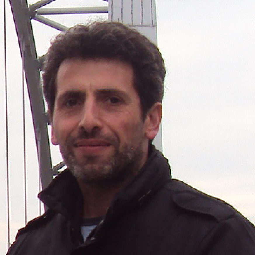 Man dark hear salt and pepper beard wearing a drak jacket 