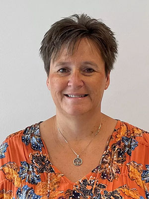 Woman with short brown hair wearing an orange flora shirt