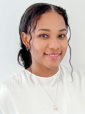 woman with dark curly hair and light brown skin wearing a white shirt smiling
