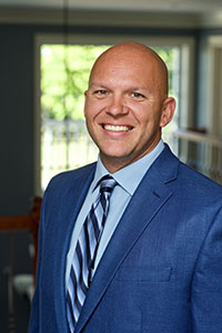 Bald man wearing a blue suit smiling