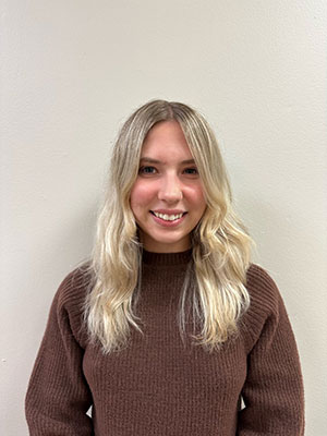 white woman with blonde hair wearing a brown sweater