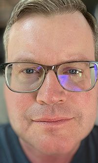 White man wearing glasses wearing a blue shirt