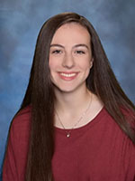 Girl with long straight brown hair smiling wearing a red shirt