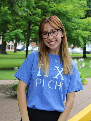 white woman with red hair wearing glasses a light blue shirt