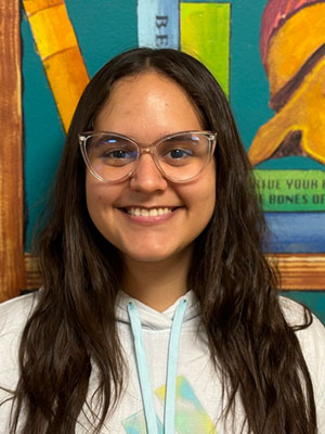 Smiling woman with long dark brown hair wearing a grey hoodie