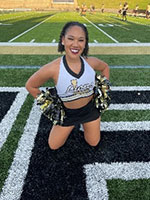 Smiling girl with short dark hair and brown skin, weariing a cheer uniform