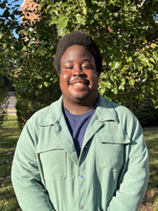 man with brown skin black hair wearing a black shirt and mint jacket