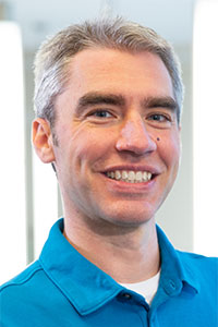 Man with grey hair wearing a blue collared shirt