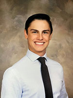 Man with dark brown hair smiling wearing a white shirt and black tie