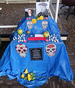 Blud day of the dead ofrenda with candy skulls chocolate, apples, photographs and yellow roses, and Texas flag