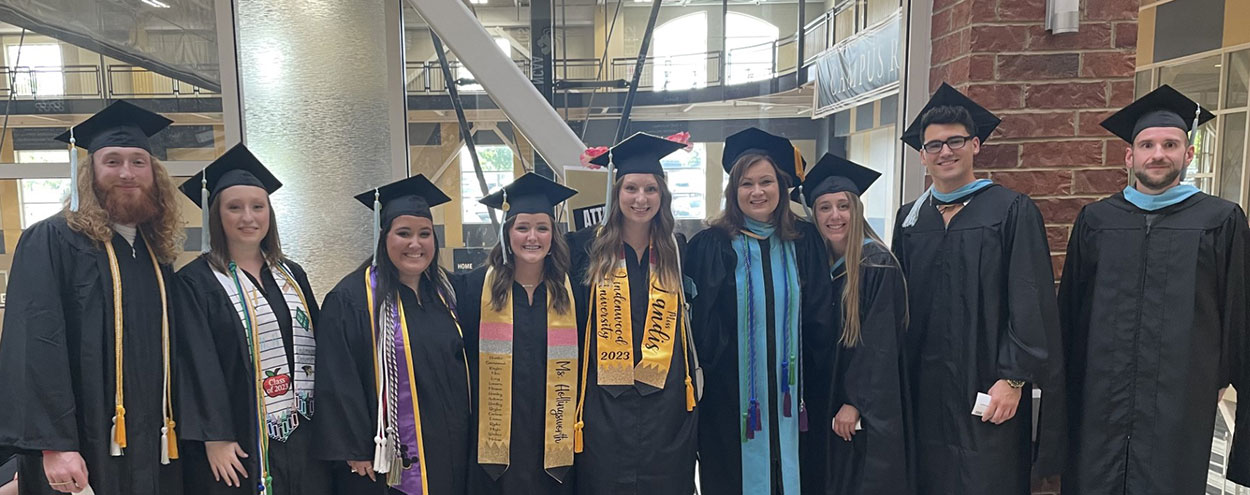 Student teaching students and faculty pose at graduation.