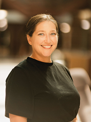 White woman, blue eyes long brown hair standing in front of lake