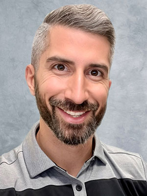 Man with dar brown hair wearing a dark color suit in front of a gradient background