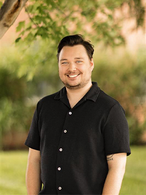 White man, blue eyes, brown hair, black glasses, light brown beard
