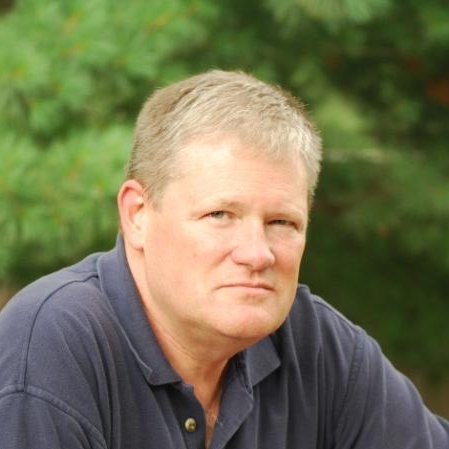 Older white man with blue eyes wearing a dark blue collard shirt