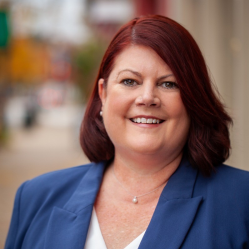 white woman with red hair wearing a blue suit