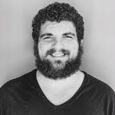 Black and white photo of smiling man with curly hair and a beard