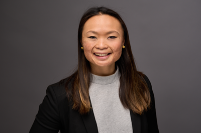 woman with dark hair wearing a grey shirt and dark suit jacket