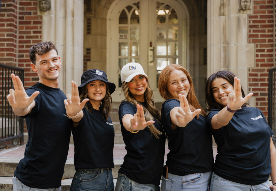 group of five social media ambassador students posing with their fingers making an "L" shape