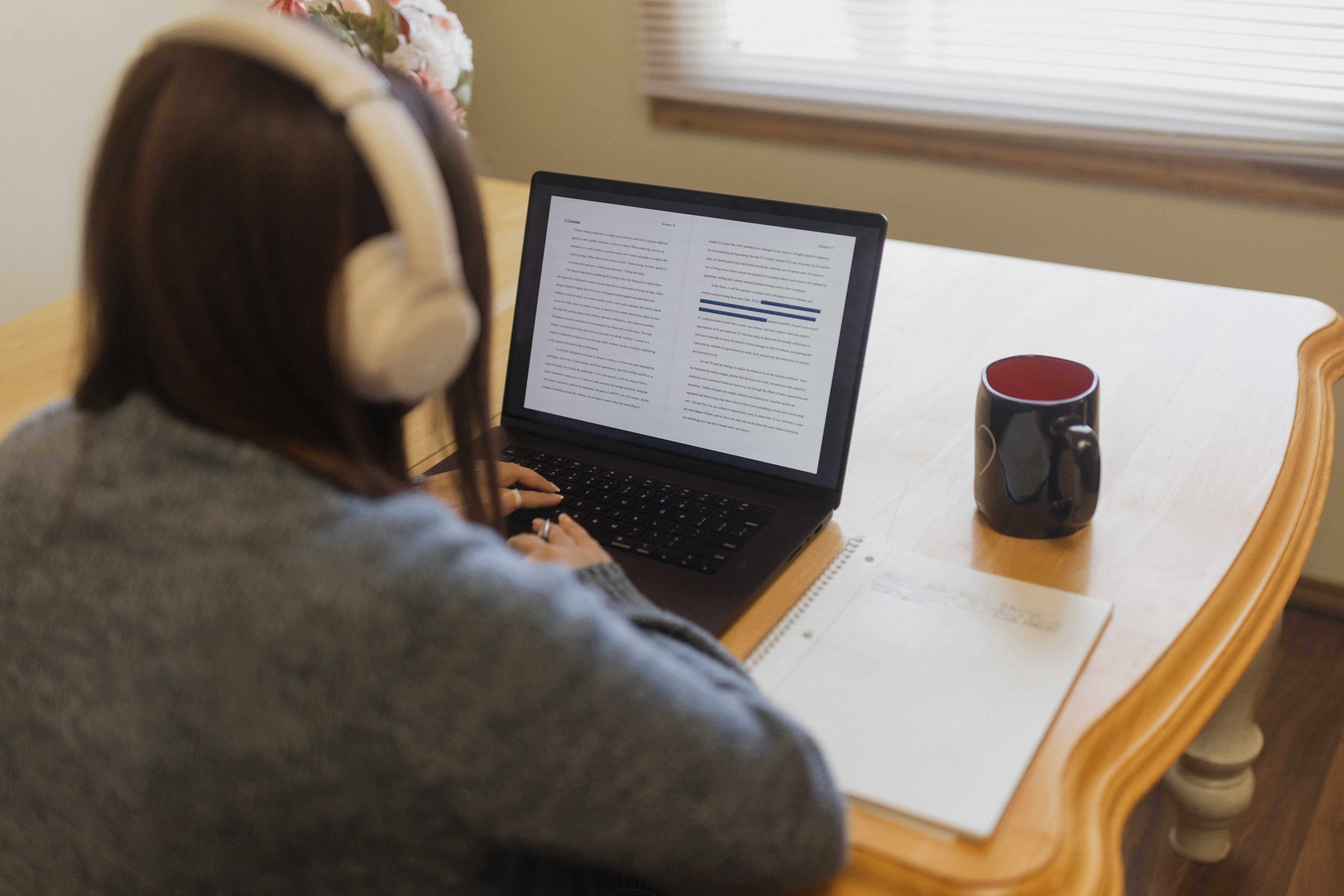 Brunette woman working on creative writing project on her laptop wearing headphones